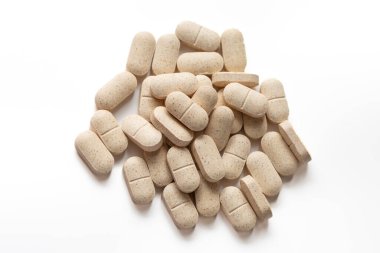 El değmemiş beyaz yüzeyde benekli desenli doğal bej takviye kapsüllerinin toplanması. İlaç pazarlama, sağlık kampanyaları ve sağlık hizmetleri içeriği için mükemmel..