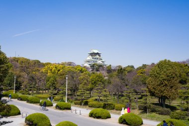 Ağaçlı ve bulutsuz gökyüzü olan Osaka şatosunun manzarası