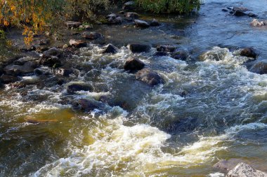 Engebeli nehirdeki kayaların üzerinden hızla akan suyun yakınlaşması