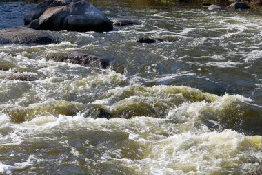 Engebeli nehirdeki kayaların üzerinden hızla akan suyun yakınlaşması