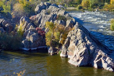 Sonbaharda ıssız kayalıklarda akan akıntılarla dağ nehrinin yukarısından manzarayı seyret. Dalgalar, sprey, köpük ve kayalıklar
