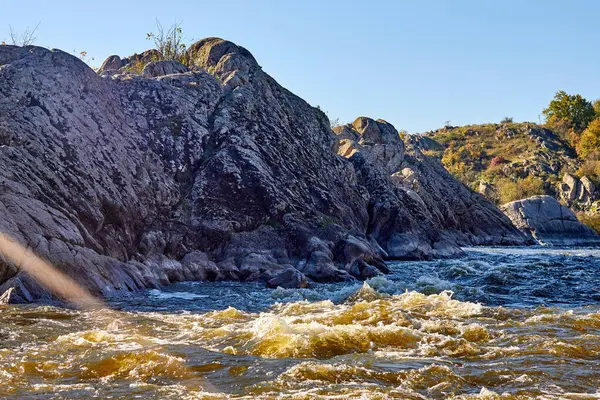 Sonbaharda ıssız kayalıklarda akan akıntılarla dağ nehrine bakın. Dalgalar, sprey, köpük ve kayalıklar