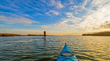 Gün batımında mavi kanonun pruvasından sonbahar gölüne bakın. Sonbahar ya da kış kanosu.