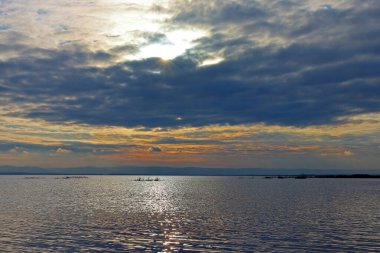 Sakin göl üzerinde gün batımı ve kış nehri veya gölde bulutlu gökyüzü