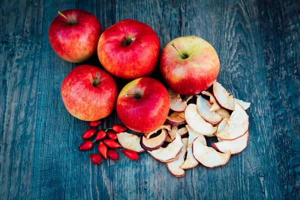 Apples, dried apples and rose hips lie on a dark wooden table Autumn. High quality photo