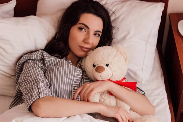 一个年轻漂亮的女孩穿着睡衣和一只泰迪熊睡在床上 高质量的照片 — 图库照片