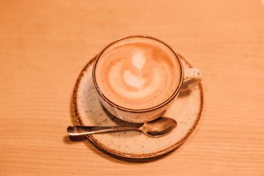 Kahverengi arka planda sütlü bir fincan kahve. Masada sıcak kapuçino var. Yüksek kalite fotoğraf