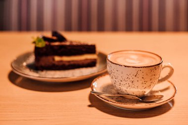 Kahverengi arka planda sütlü bir fincan kahve. Masada sıcak kapuçino var. Yüksek kalite fotoğraf