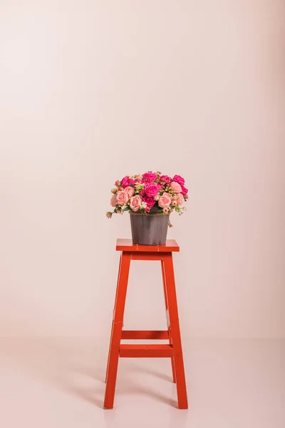 Bouquet of roses in a bucket on a red high chair. High quality photo