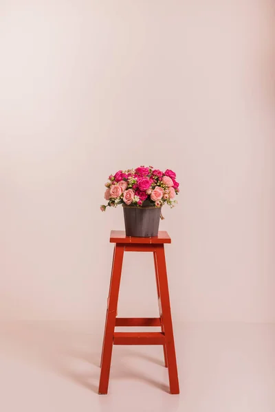 Bouquet of roses in a bucket on a red high chair. High quality photo