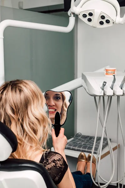 Uma Mulher Numa Cadeira Dentista Olha Para Dentes Espelho Foto — Fotografia de Stock