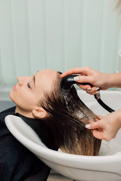 The hairdresser washes the clients hair in the salon. Hair dyeing and cutting. High quality photo