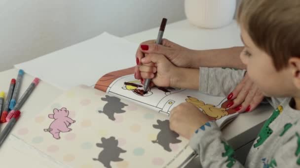 Een Jongetje Schildert Foto Met Markeringen Thuis Tafel Hoge Kwaliteit — Stockvideo