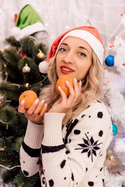 A woman in a sweater holds tangerines in her hands for Christmas. New Years Eve food. High quality photo