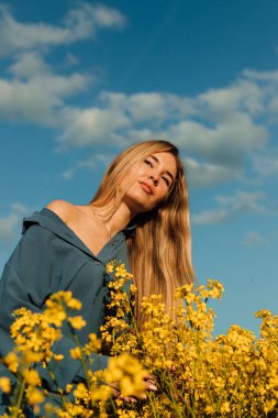 Kolza tohumu tarlasında duran güzel genç bir kadın. Mavi gökyüzüne karşı tecavüz tarlası. Yüksek kalite fotoğraf