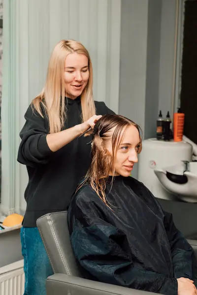 A hairdresser cuts a blondes hair in a beauty salon. Womens haircut. High quality photo