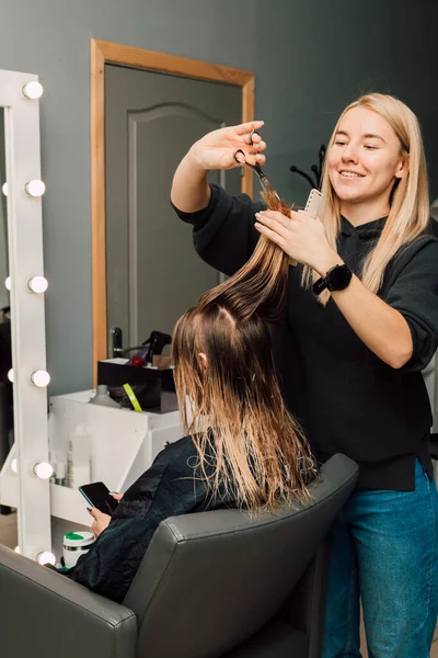 美容院の美容師が美容室でブロンドの髪を切っています 女性のヘアカット 高品質の写真 — ストック写真