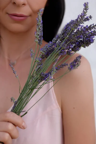Woman with a bouquet of lavender on a white background. Aromatherapy with herbs from the garden. High quality photo