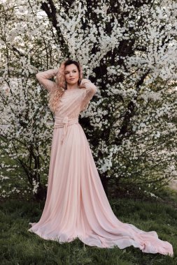 Bir kız baharda çiçek açan bir ağacın yanında duruyor. Kiraz çiçekleri. Yüksek kalite fotoğraf