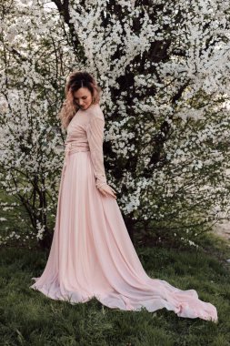 Bir kız baharda çiçek açan bir ağacın yanında duruyor. Kiraz çiçekleri. Yüksek kalite fotoğraf