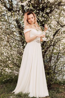 Bir kız baharda çiçek açan bir ağacın yanında duruyor. Kiraz çiçekleri. Yüksek kalite fotoğraf