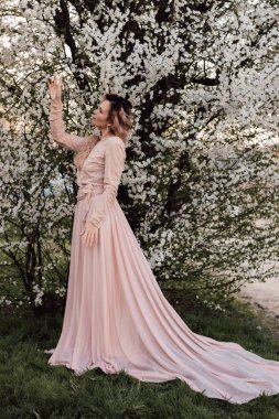 Bir kız baharda çiçek açan bir ağacın yanında duruyor. Kiraz çiçekleri. Yüksek kalite fotoğraf