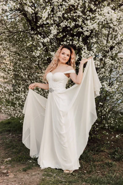 Bir kız baharda çiçek açan bir ağacın yanında duruyor. Kiraz çiçekleri. Yüksek kalite fotoğraf