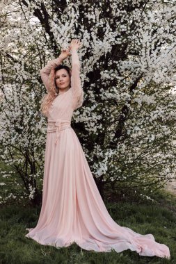 Bir kız baharda çiçek açan bir ağacın yanında duruyor. Kiraz çiçekleri. Yüksek kalite fotoğraf