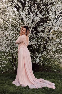 Bir kız baharda çiçek açan bir ağacın yanında duruyor. Kiraz çiçekleri. Yüksek kalite fotoğraf