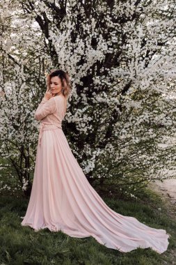 Bir kız baharda çiçek açan bir ağacın yanında duruyor. Kiraz çiçekleri. Yüksek kalite fotoğraf