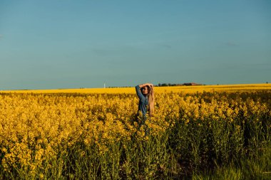 Kolza tarlasında güzel bir kadın. Ukrayna bayrağının sembolizmi: sarı-mavi arka plan. Yüksek kalite fotoğraf