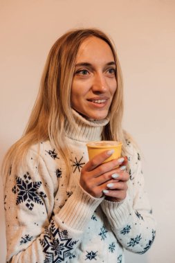 Bir bardak kahveyle Noel süveteri giyen bir kadın. Evde Noel zamanı. Yüksek kalite fotoğraf