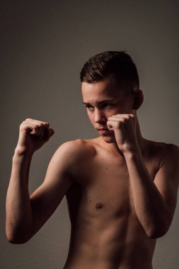 Genç bir boksör, karanlık arka planda boks eğitimi alıyor. Agresif bir spor. Yüksek kalite fotoğraf