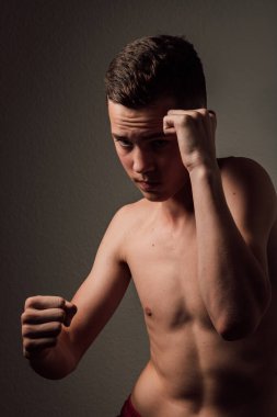 Genç bir boksör, karanlık arka planda boks eğitimi alıyor. Agresif bir spor. Yüksek kalite fotoğraf