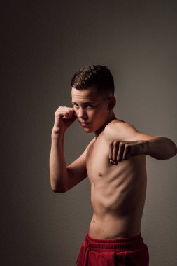 Genç bir boksör, karanlık arka planda boks eğitimi alıyor. Agresif bir spor. Yüksek kalite fotoğraf