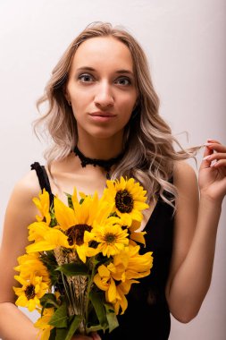 Duygusal bir kadın elinde bir buket ayçiçeği tutuyor. Yüzünde merak var. Yüksek kalite fotoğraf