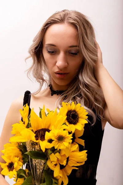 An emotional woman holds a bouquet of sunflowers in her hands. Curiosity on the face. High quality photo