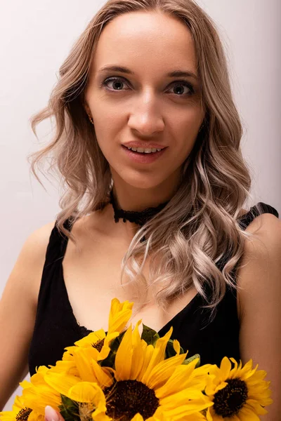 An emotional woman holds a bouquet of sunflowers in her hands. Curiosity on the face. High quality photo