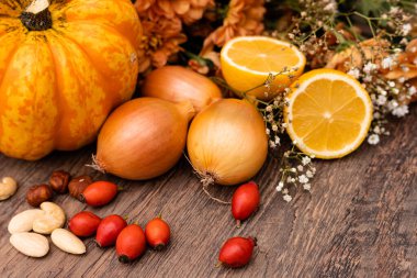 Sonbahar kompozisyonu. Masanın üzerinde balkabakları, soğanlar, fındıklar, gül kalçalar var. Yemek pişirmek. Yüksek kalite fotoğraf