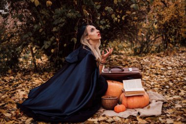 Ormandaki genç bir cadı büyü yapar, kitap okur. Ormanda sihir. Cadılar Bayramı. Yüksek kalite fotoğraf