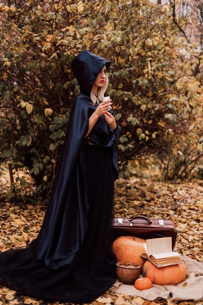 Ormandaki genç bir cadı büyü yapar, kitap okur. Ormanda sihir. Cadılar Bayramı. Yüksek kalite fotoğraf