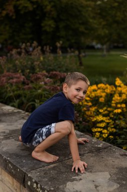 Bir çocuk parkta çiçeklerin yanında oynar. Yaz tatilinde çocuk eğlencesi. Yüksek kalite fotoğraf