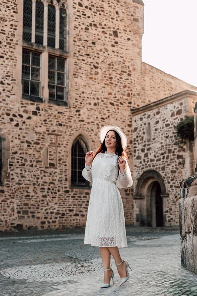 Elegant woman in hat walking in old town. Excursion in summer during your vacation. High quality photo