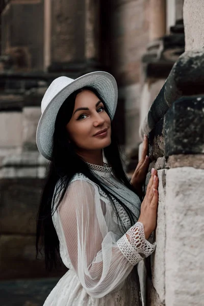 Elegant woman in hat walking in old town. Excursion in summer during your vacation. High quality photo