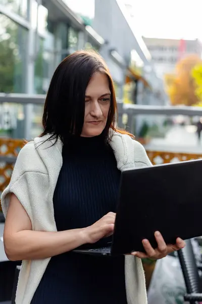 A woman in a business suit works at a laptop in a restaurant.Online Work. Online study High quality photo