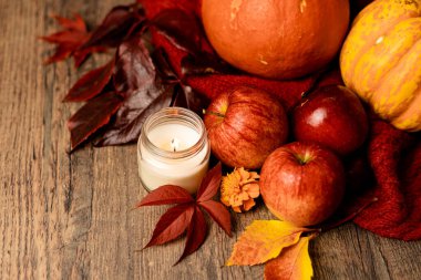 Elma ve üzüm yapraklarının yanındaki masada yanan mum. Sonbahar Kompozisyonu. Yüksek kalite fotoğraf