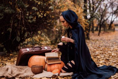 Ormandaki genç bir cadı büyü yapar, kitap okur. Ormanda sihir. Cadılar Bayramı. Yüksek kalite fotoğraf