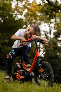 Bir çocuk gölün yakınındaki bir parkta bisiklet sürüyor. Liseli çocuğun izin günü. Yüksek kalite fotoğraf