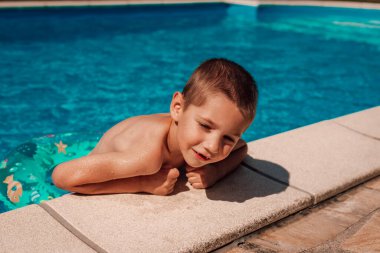 Küçük bir çocuk havuzdan çıkıyor. Bir çocuk öğle vakti sıcakta banyo yapar. Yüksek kalite fotoğraf