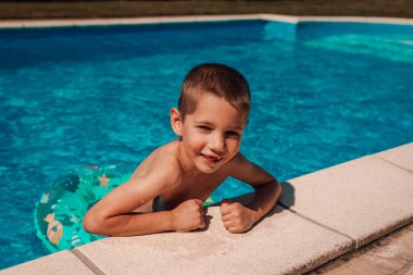 Küçük bir çocuk havuzdan çıkıyor. Bir çocuk öğle vakti sıcakta banyo yapar. Yüksek kalite fotoğraf